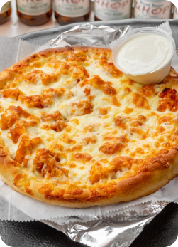 Cheese pizza on a foil-lined tray with a cup of ranch dip.