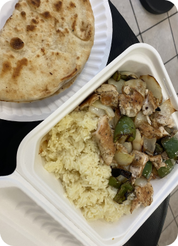 Takeout tray with chicken, peppers, onions, and rice with pita bread.